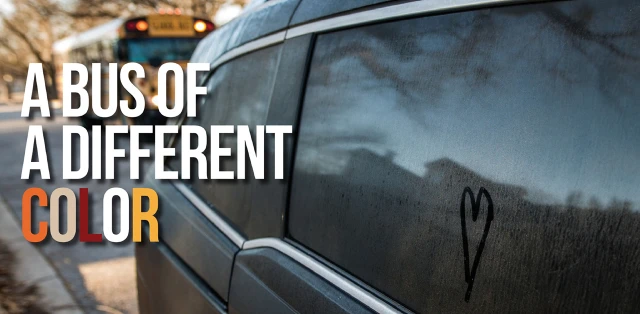 A car with a heart symbol on its windows with text displaying the phrase 'a bus of a different color' beside it.
