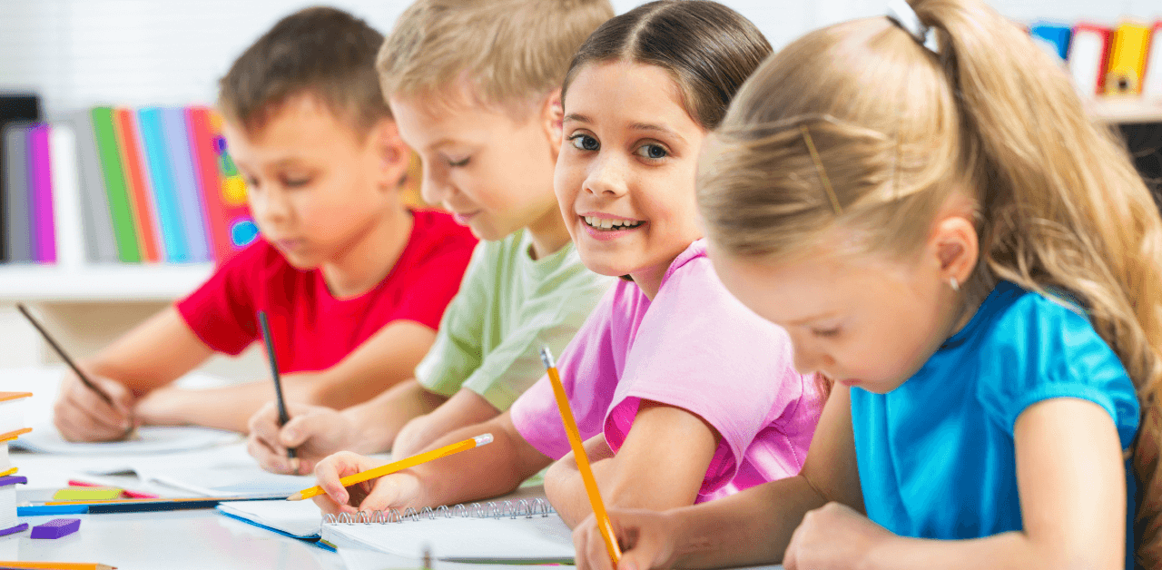 A group of children at a table, using pencils and paper, immersed in artistic and educational activities together.