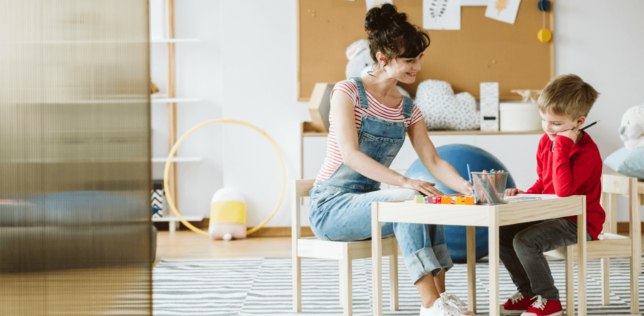 A woman and a child are seated at a table, engaged in a learning activity together.