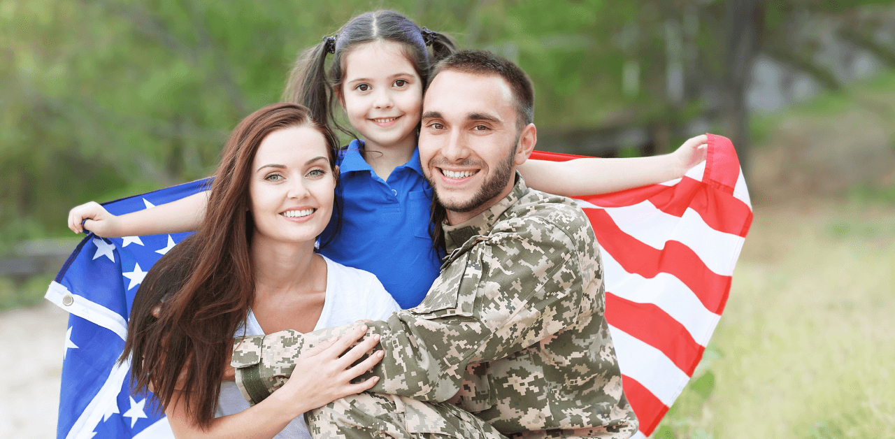 A military family stands proudly together, holding an American flag.