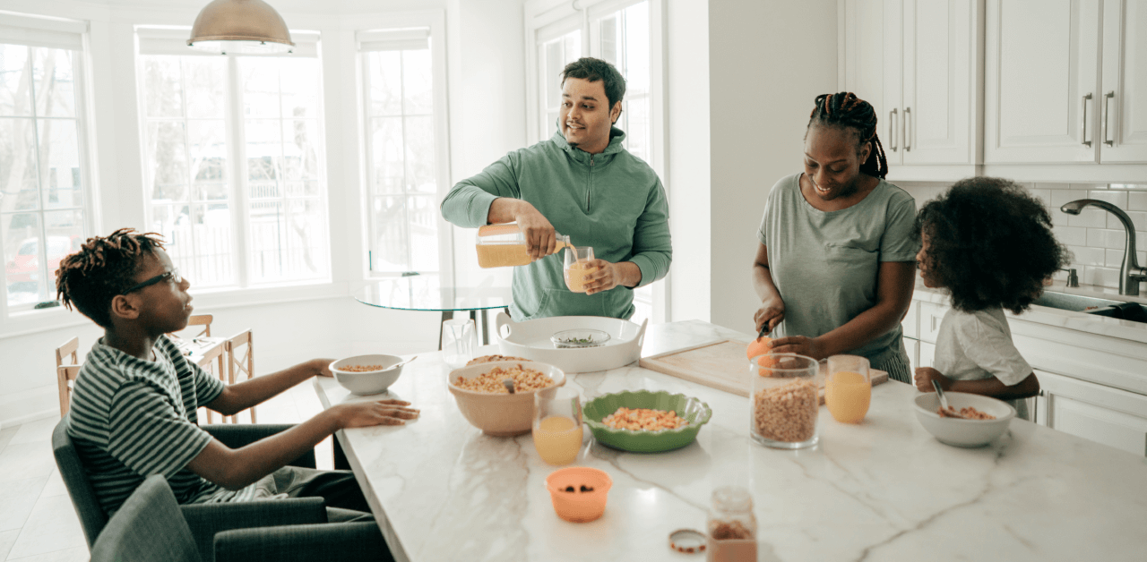 A family gathers around a kitchen table, sharing a meal and enjoying each other's company.