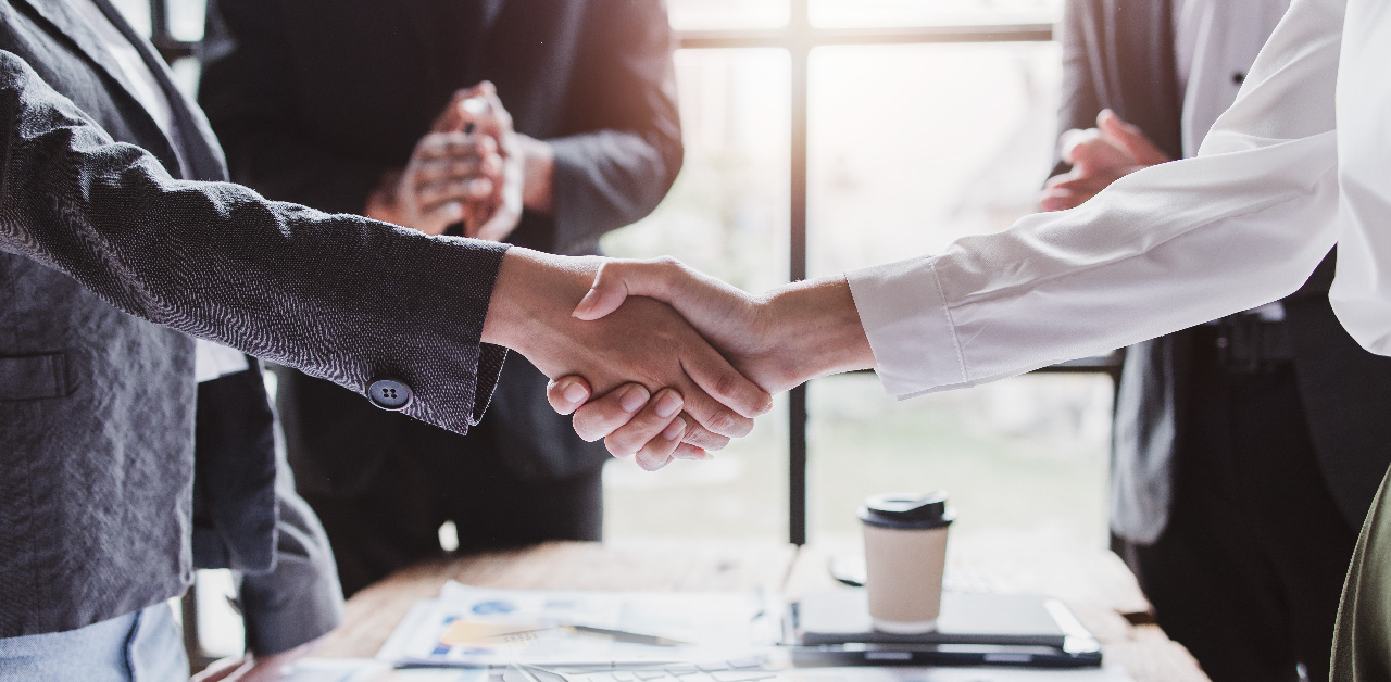 two_business_individuals_shaking_hands_across_a_table_representing_agreement_and_mutual_understanding_in_a_professional_setting