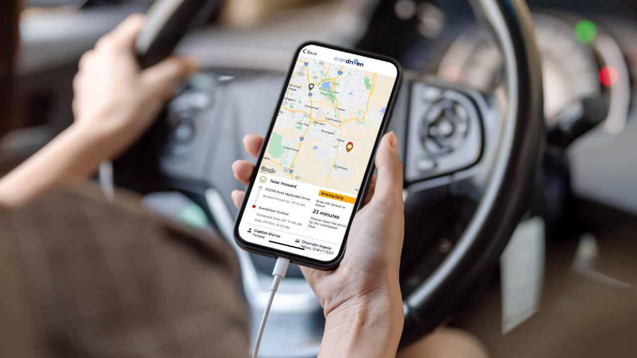 Person using the EverDriven VIP app for real-time student transportation tracking while driving