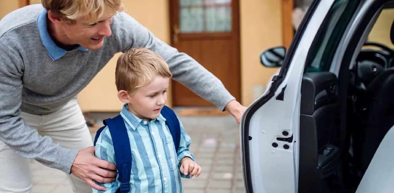 An adult assists a small child with a backpack as they carefully guide them into the car, offering support for a safe and smooth entry.