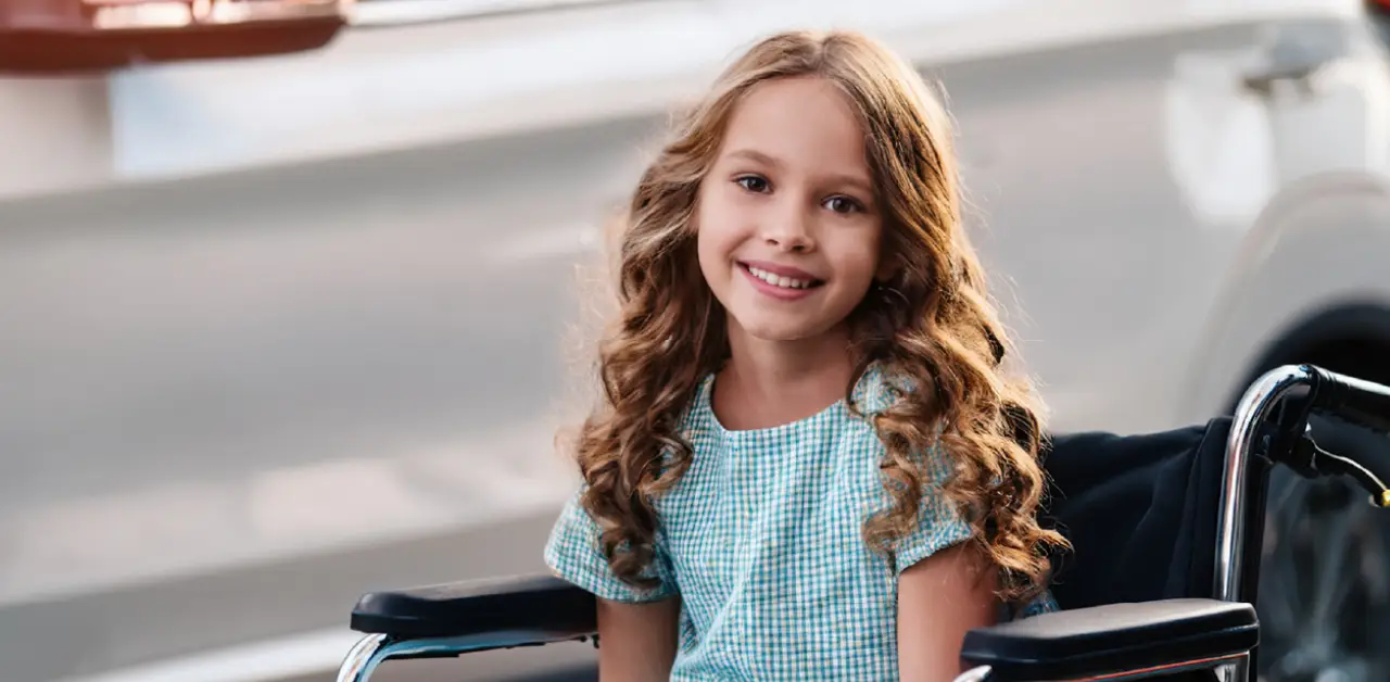 A smiling elementary schoolgirl in a wheelchair waits to board ride home from school.