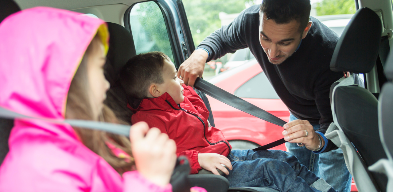 Driver securing children with seatbelts in a car