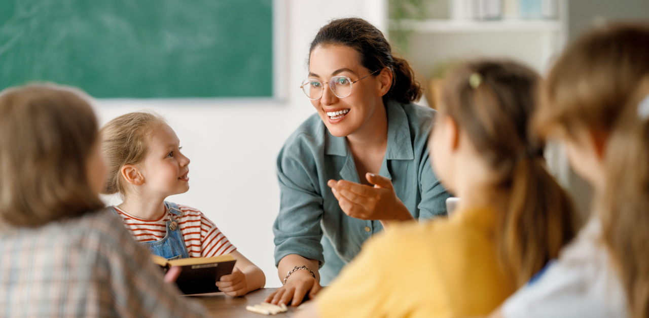 A smiling teacher engages with young students in a classroom, representing Pittsburgh Public Schools’ commitment to safe and inclusive student transportation.