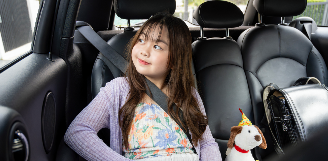 Young student sitting safely in a car with seatbelt fastened