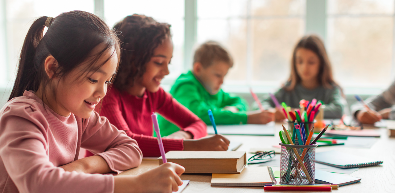 Students writing together at a classroom table during school