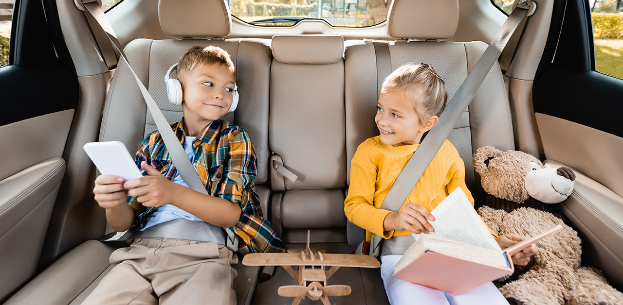 children seated and buckled in the back seat of a small vehicle during a school ride