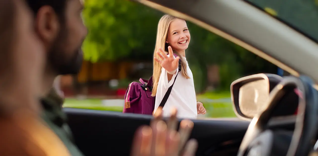 student waving goodbye to a driver after being dropped off at school