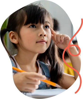 A young girl with a ponytail attentively listens in class, holding a pencil. Behind her, students engage in learning.
