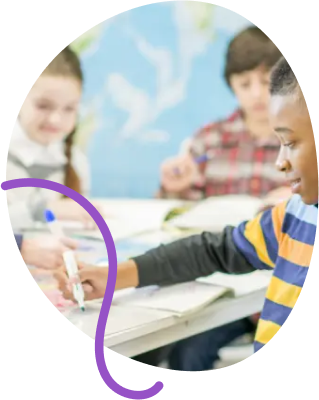 Children studying together at a table with a globe in a classroom.