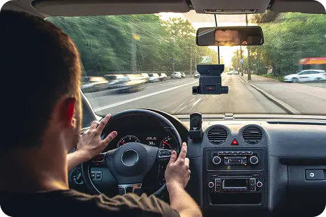 A man driving a car, hands positioned on the steering wheel, concentrating on the road ahead.