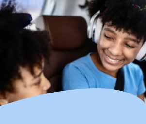 Two children smiling in a car, one in headphones and a seatbelt. Text below reads "How We Prioritize Accident Prevention."