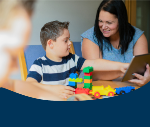 A boy in striped shirt builds with colorful blocks at a table. A smiling woman in a blue shirt shows him a tablet. Caption: “IEP and 504 Transportation Rights and Eligibility.”