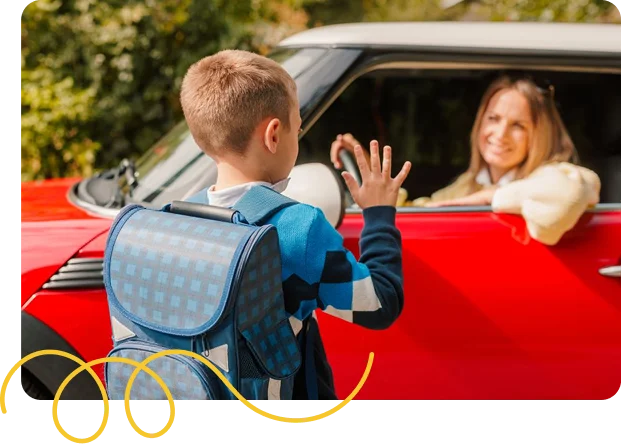 Boy waving goodbye to a woman behind the seat of a car.