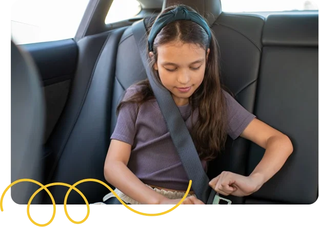 Girl fastening her seatbelt in the back seat of a car.