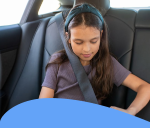 Girl fastening her seatbelt in the back seat of a car.