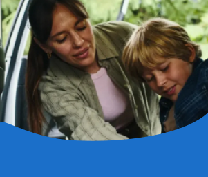 A woman helps a young boy buckle his seatbelt in a car, conveying care and safety. Text below reads "Redefining Safe Student Transportation."