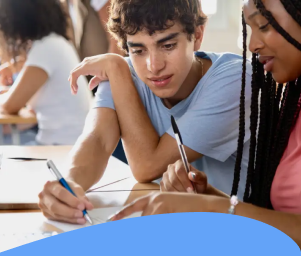 Two students sitting at a desk, collaborating on paperwork. They appear focused and engaged. Text below reads: "Students Experiencing Housing Instability."