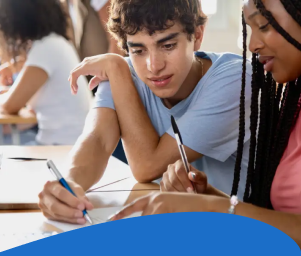 Two students sitting at a desk, collaborating on paperwork. They appear focused and engaged. Text below reads: "Students Experiencing Housing Instability."