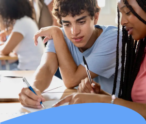 Two students sitting at a desk, collaborating on paperwork. They appear focused and engaged. Text below reads: "Students Experiencing Housing Instability."