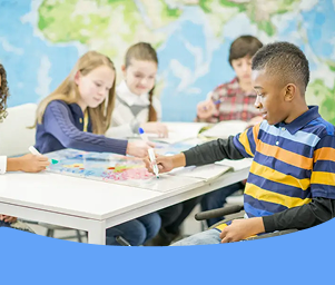 Children studying together at a table with a globe in a classroom.