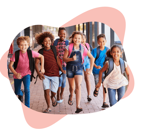 A diverse group of six happy children with backpacks run down a sunlit sidewalk, smiling joyfully.